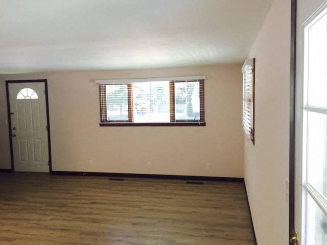 an empty living room with wood floors and a window