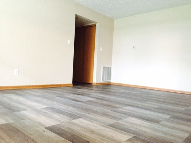 an empty living room with wood flooring and white walls