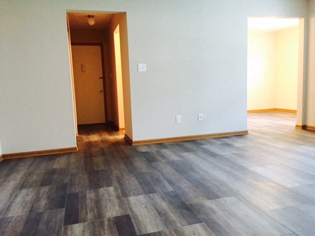 an empty living room with wooden floors and white walls