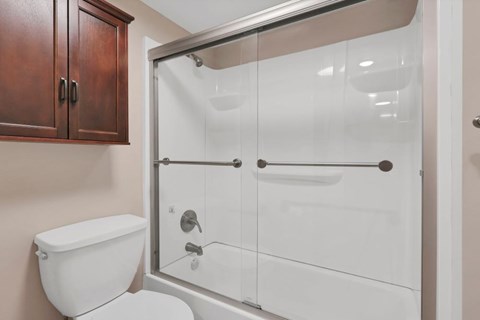 A white toilet sits next to a walk-in shower with a glass door.