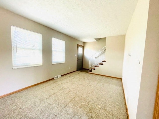 an empty living room with a staircase and two windows