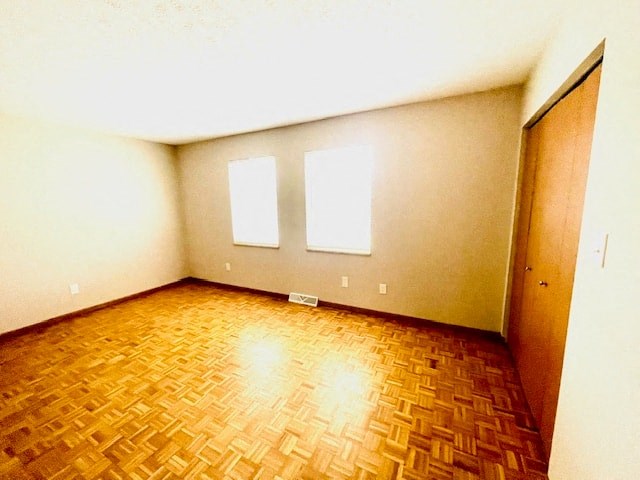 an empty room with two windows and a wooden floor