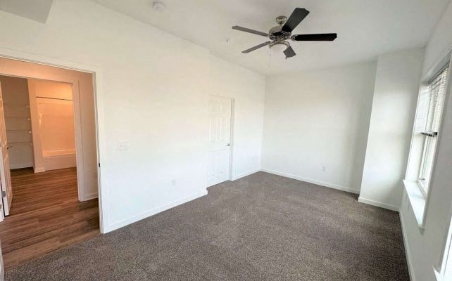 an empty living room with a ceiling fan