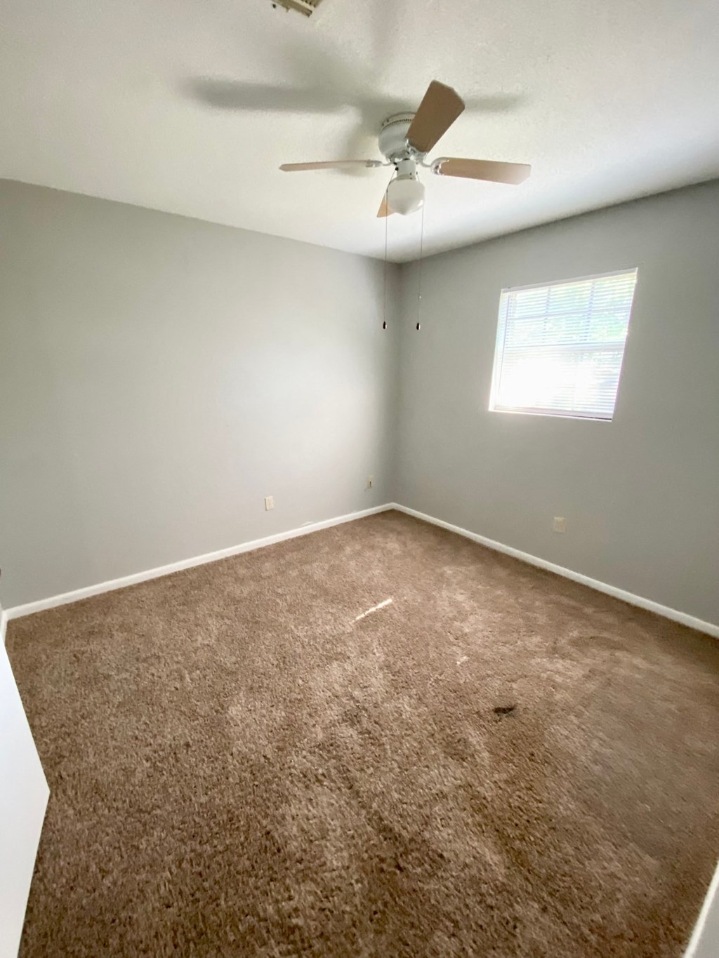 an empty room with a ceiling fan and a window