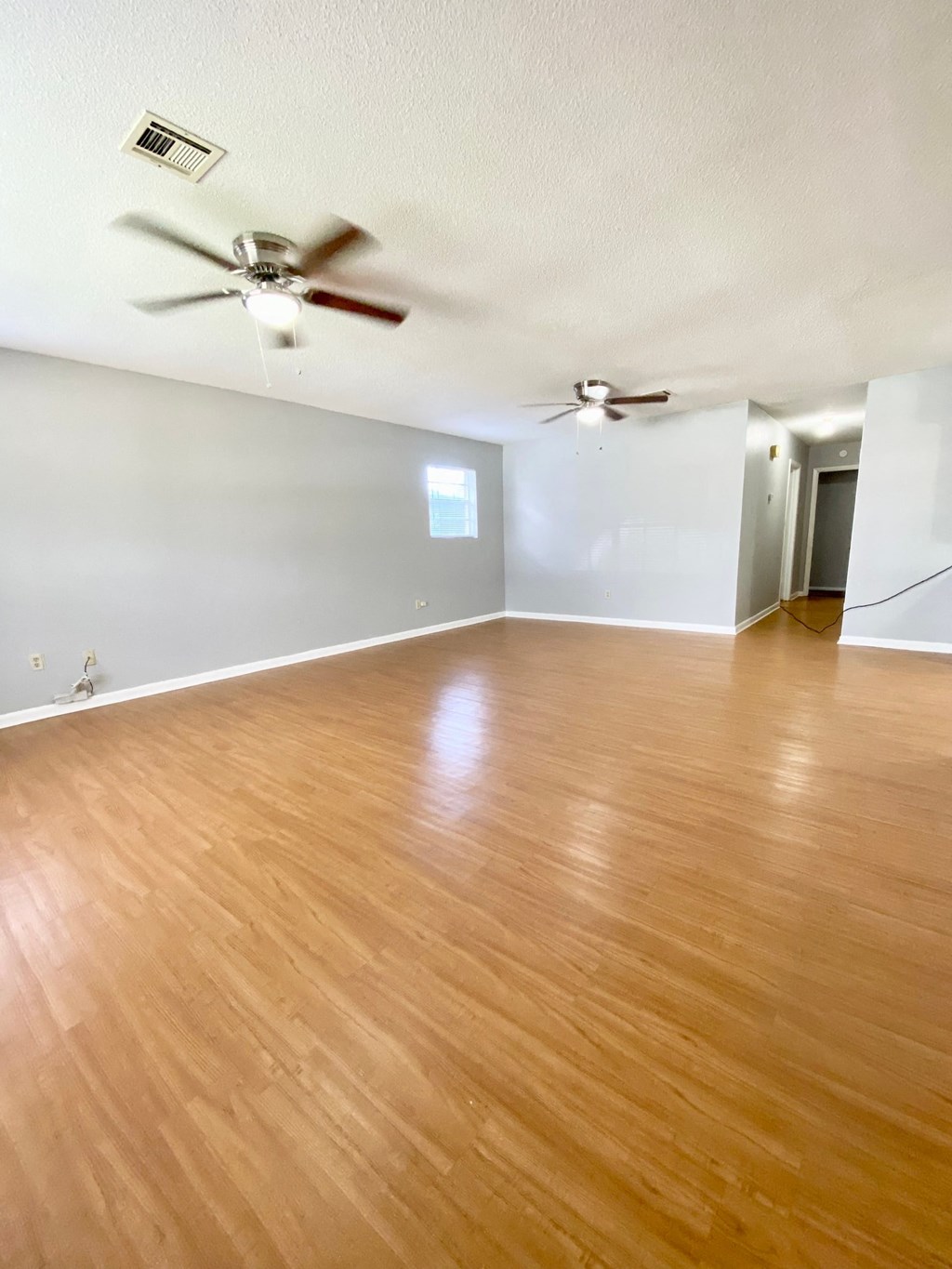 an empty living room with wood floors and a ceiling fan