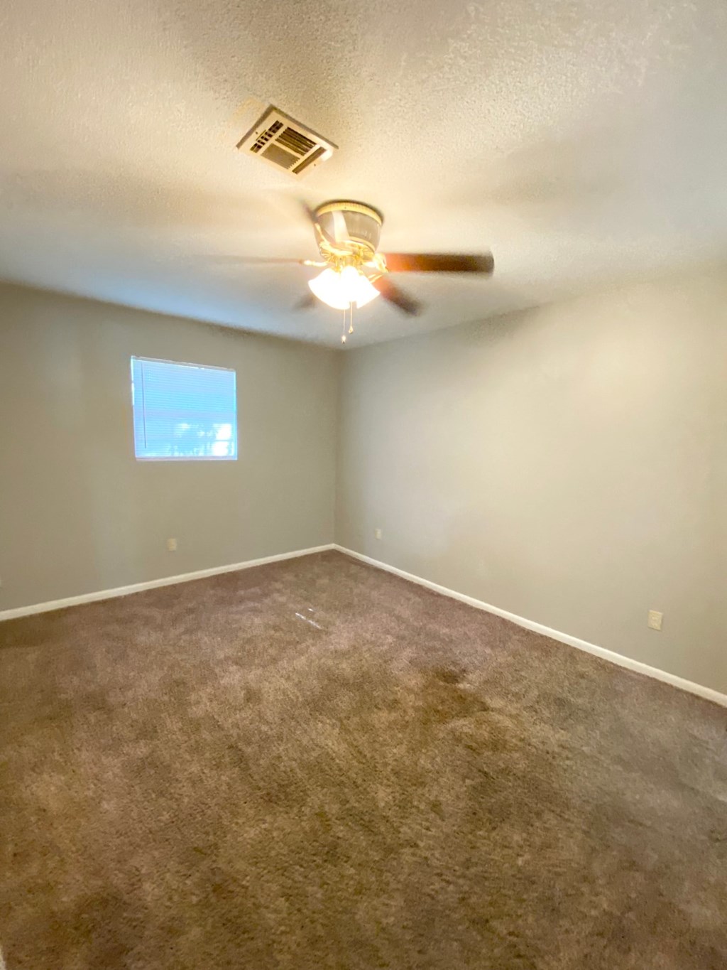 an empty living room with a ceiling fan and a window