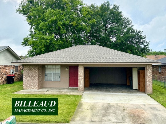 a small brick house with a garage and a tree