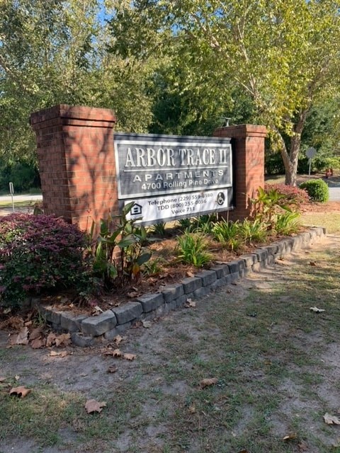 a sign for arbor trace park in front of a brick wall