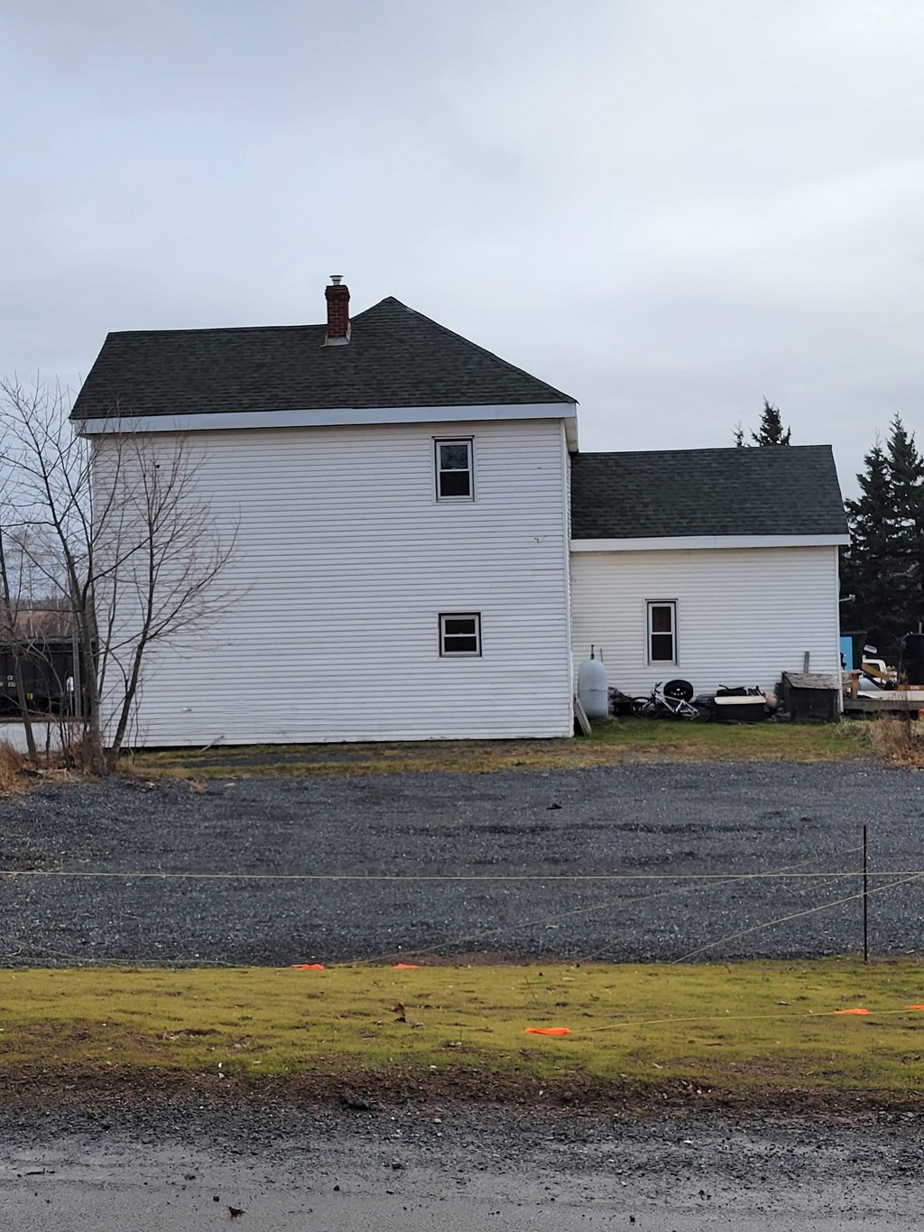 a white house with a black roof and a gravel road