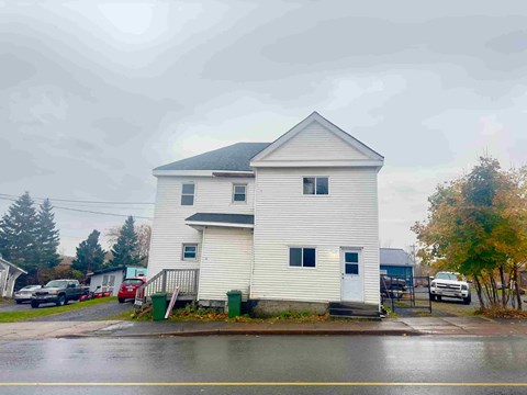 a white house on the corner of a rainy street