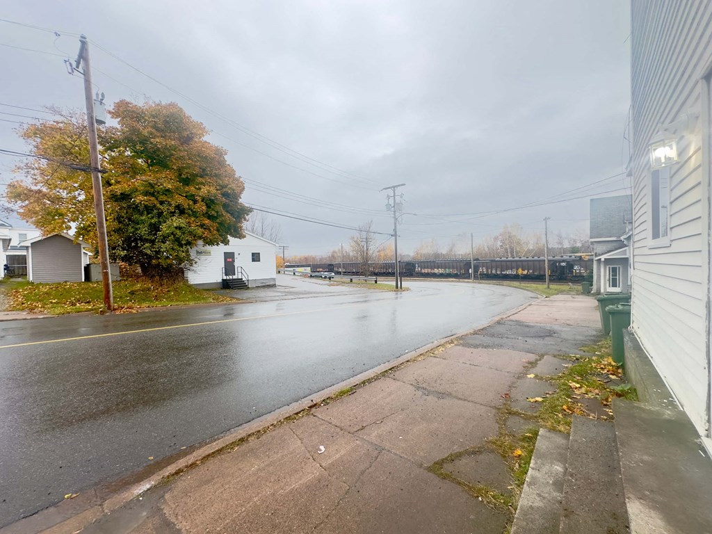 an empty street with houses and a bridge in the distance