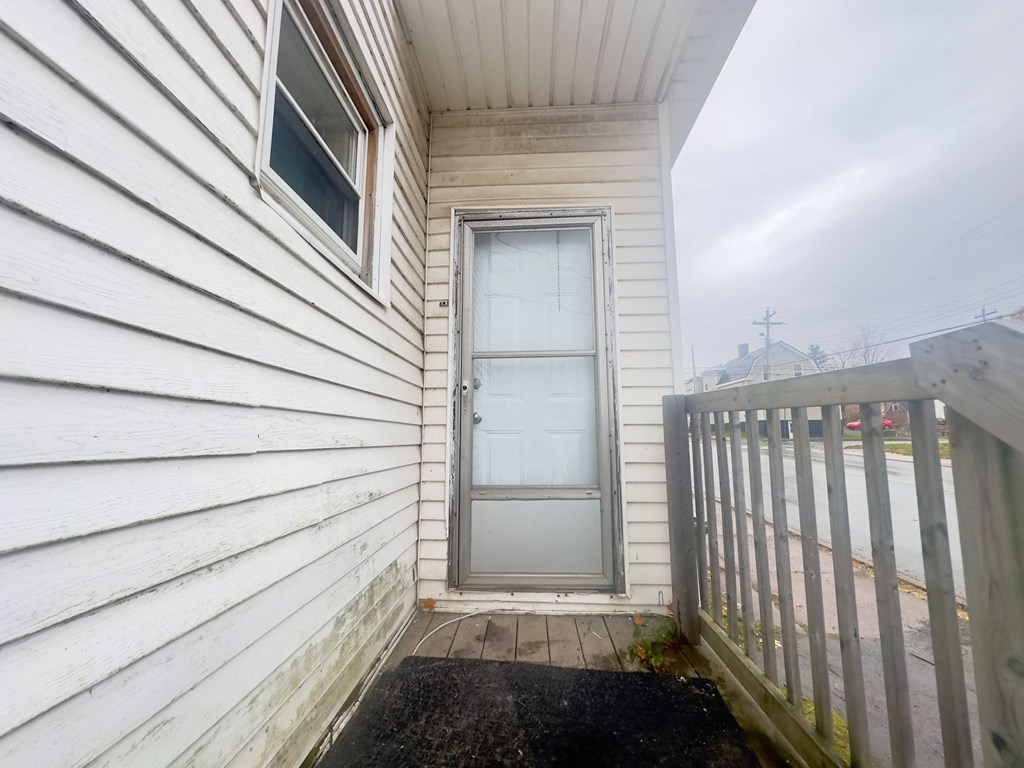 a door on the side of a white house with a wooden fence