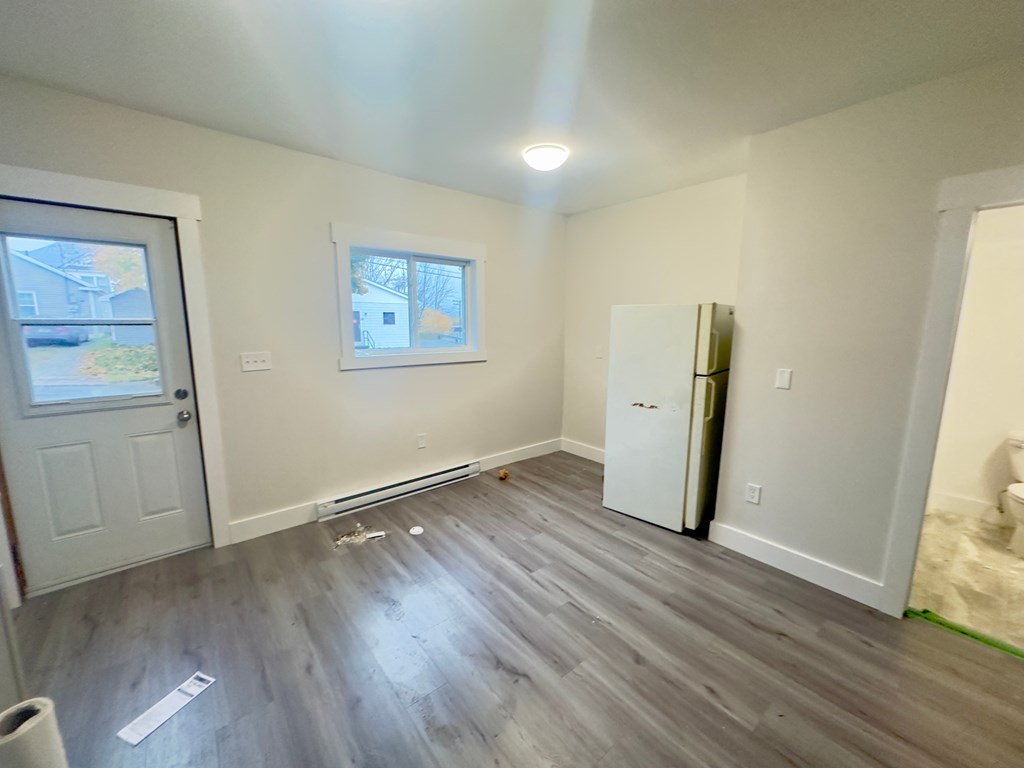 an empty living room with white walls and a white refrigerator