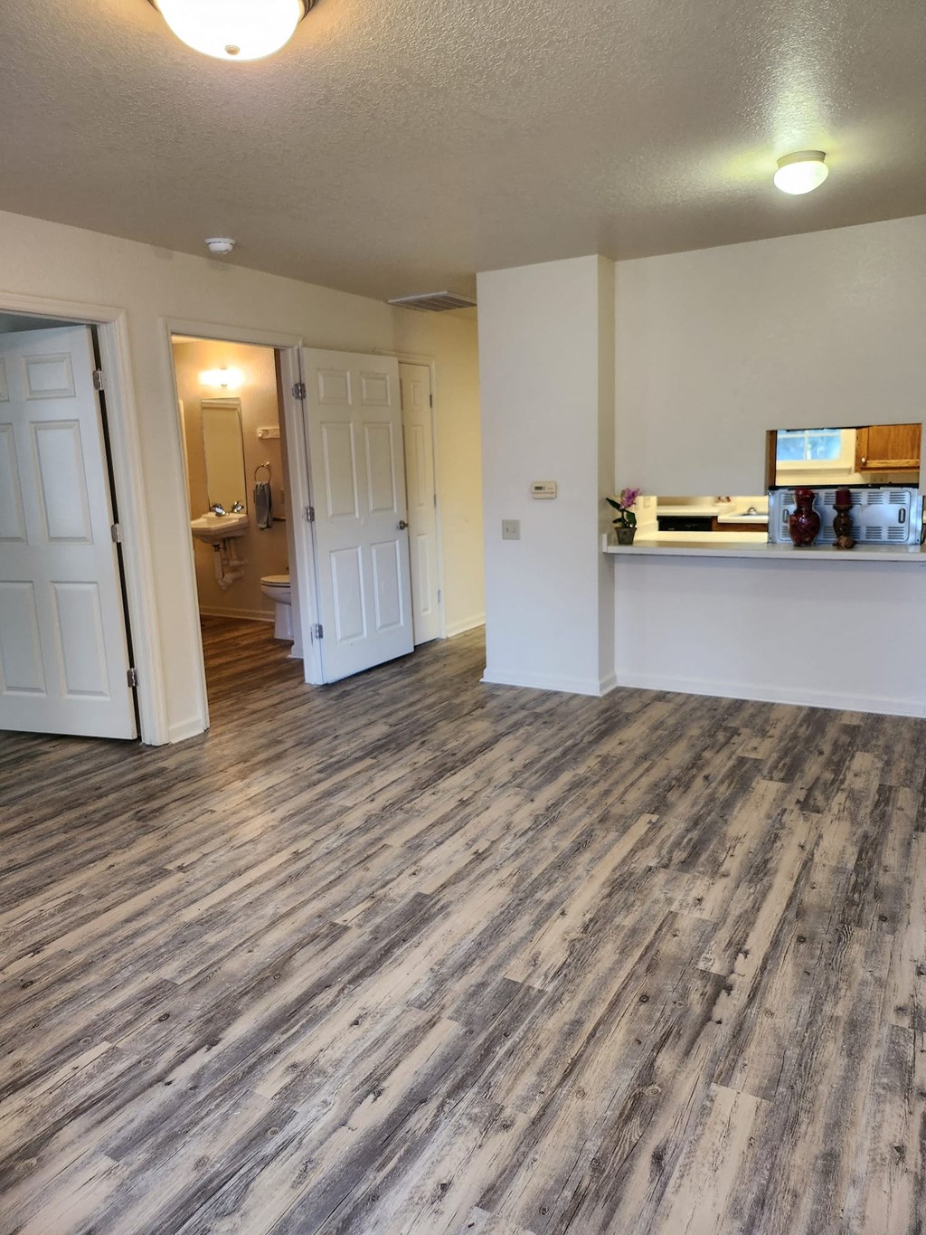 a living room and kitchen with wood floors and white walls