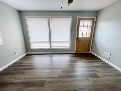 an empty living room with wood floors and a door