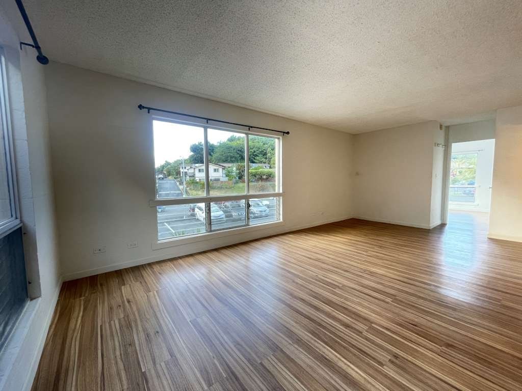 A room with wooden flooring and a sliding glass door leading to a street.