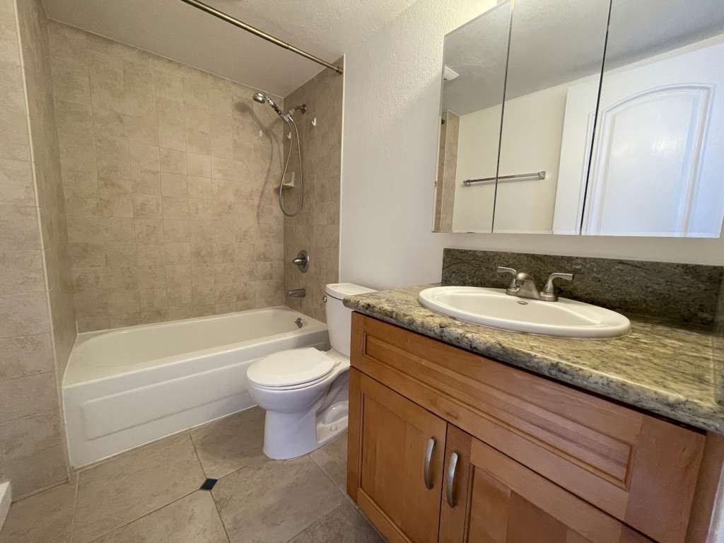 A bathroom with a white tub, sink, and toilet.