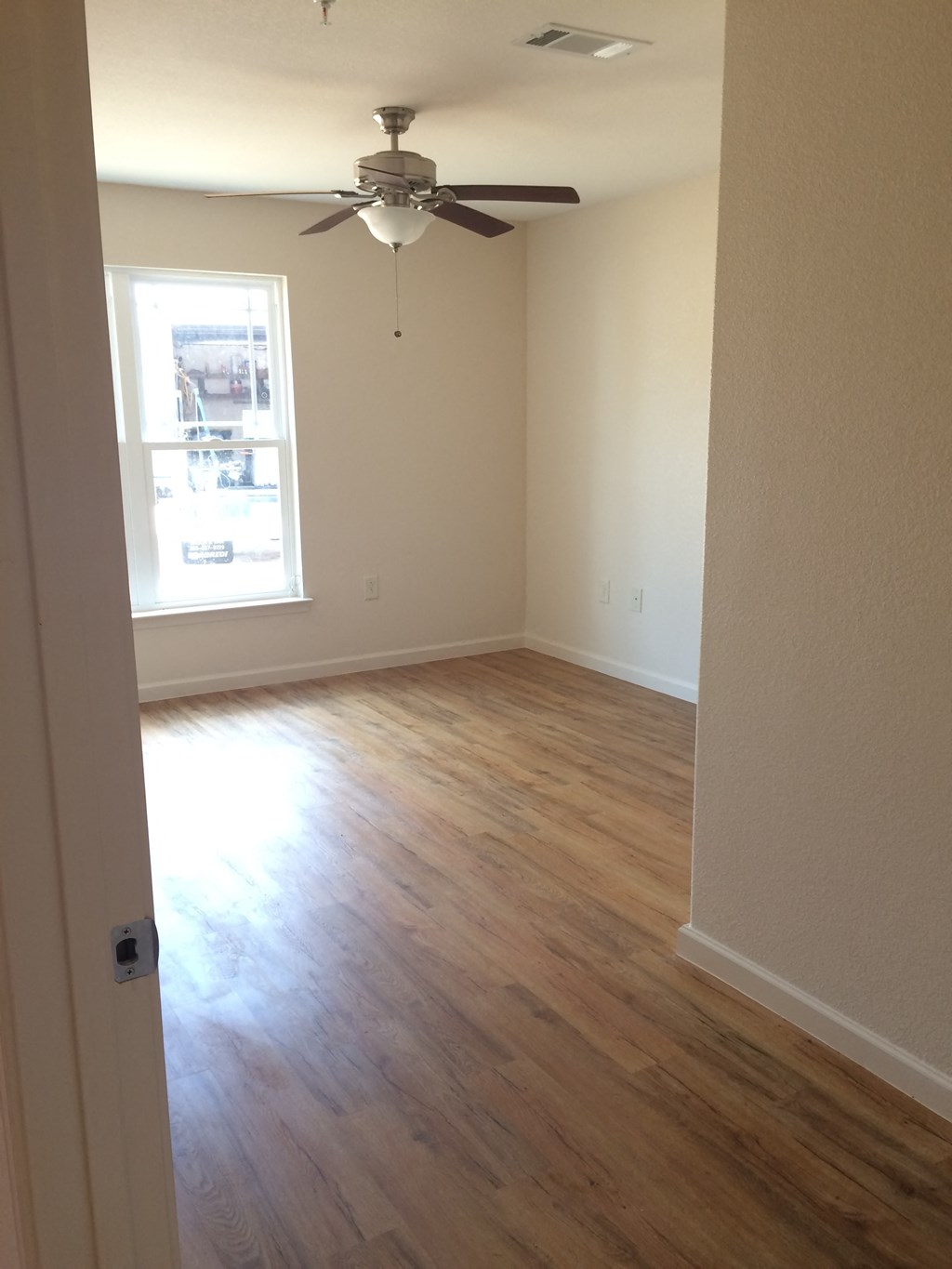 an empty living room with wooden floors and a ceiling fan