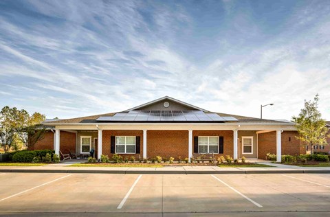 the front of a brick building with a parking lot