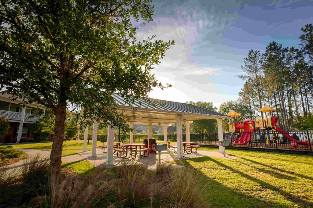 a pavilion with picnic tables and a playground in the background
