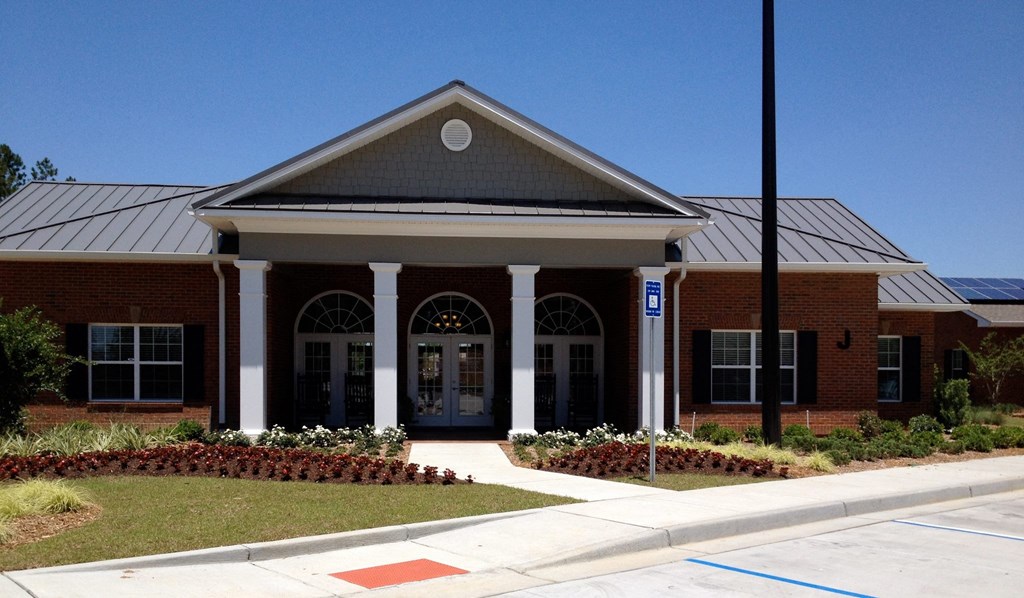 the front of a brick building with white pillars and a sidewalk