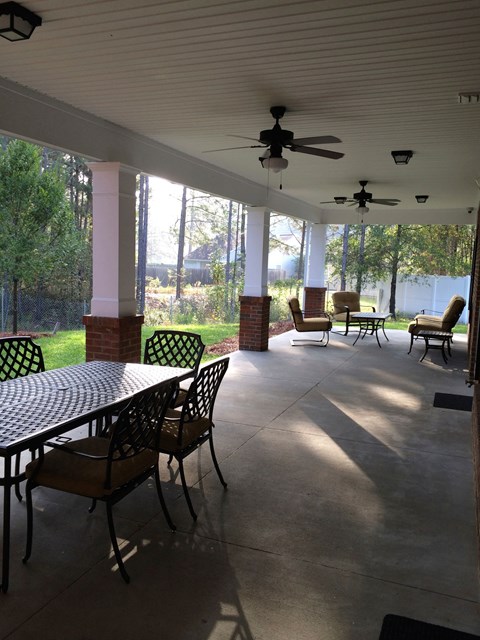 a covered porch with a table and chairs and ceiling fans