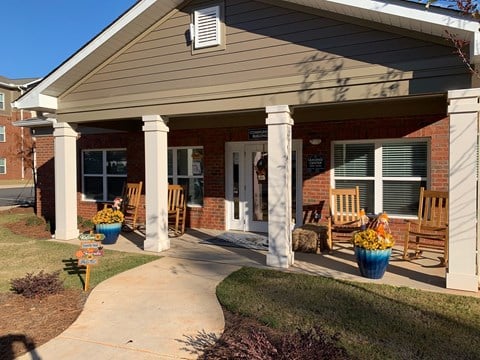 front porch of a brick house with rocking chairs and potted plants