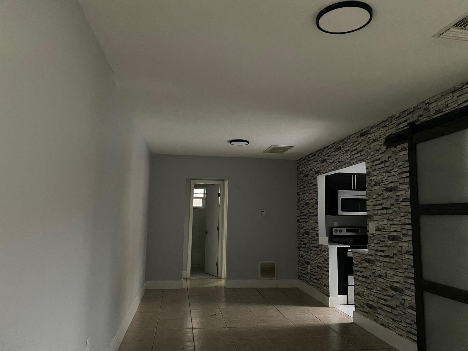 a hallway with a stone wall and a door into a room