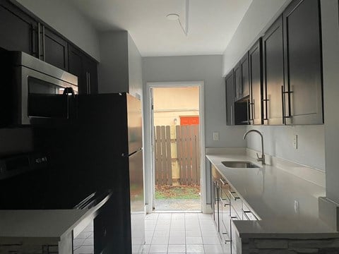 a kitchen with black cabinets and a door to a backyard