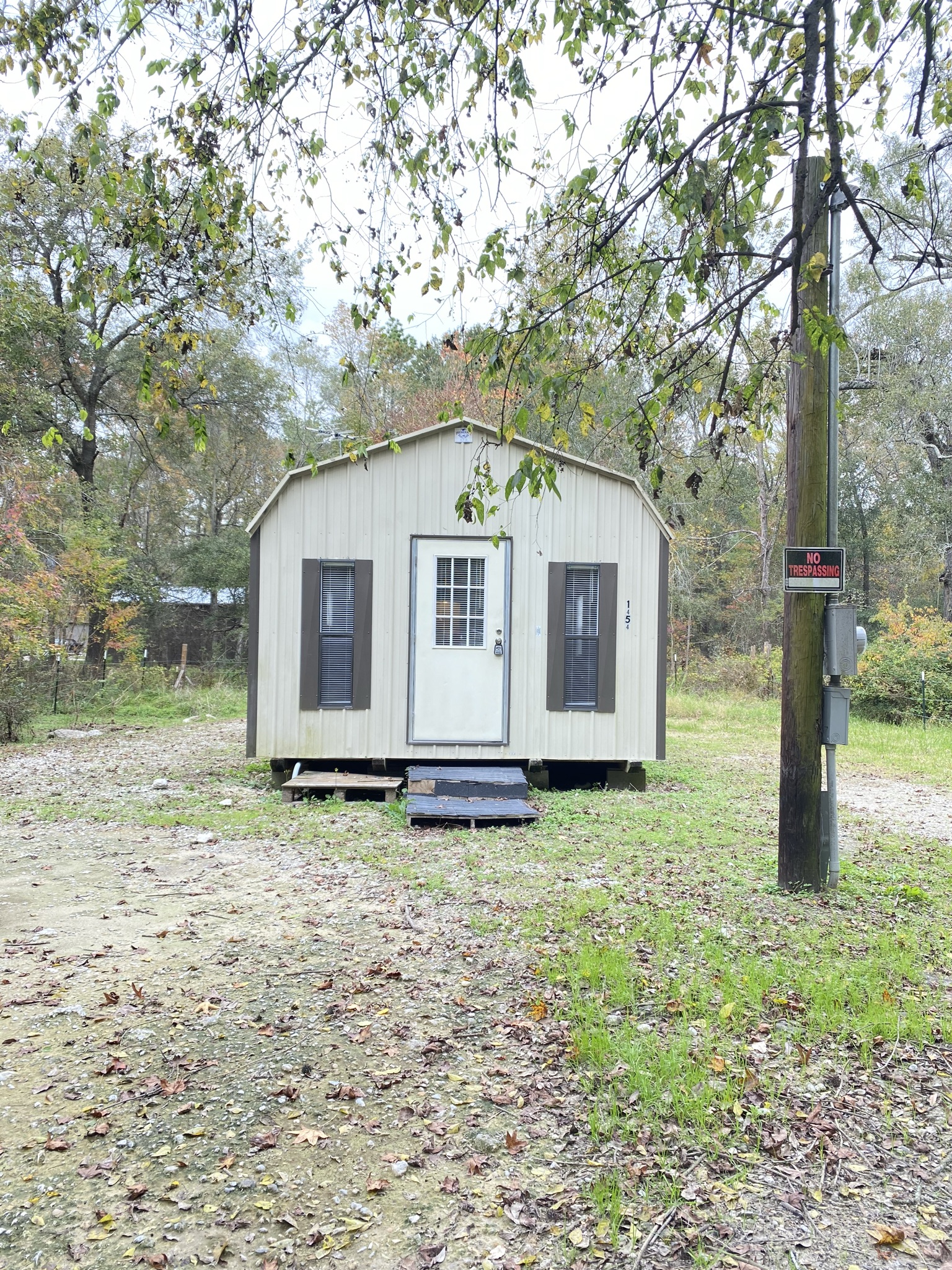 a tiny house on a dirt road next to a tree