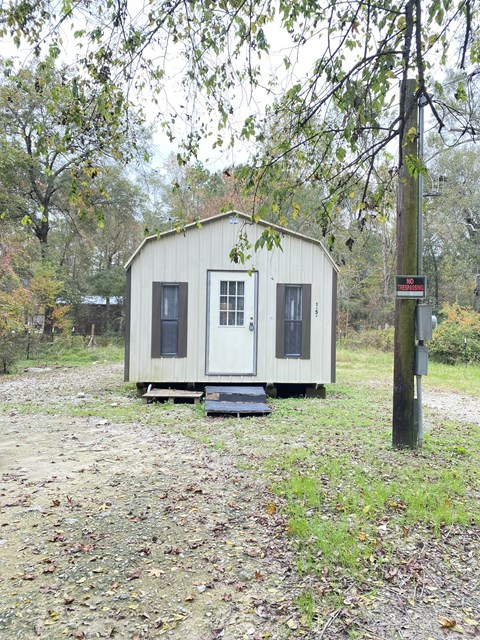 a tiny house on a dirt road next to a tree