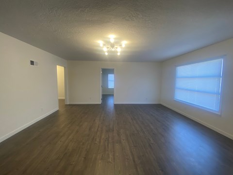 an empty living room with wood floors and a large window