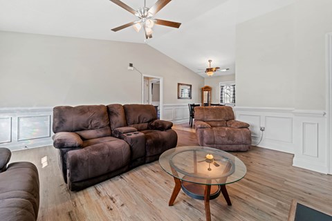 A living room with a brown couch and a glass coffee table.