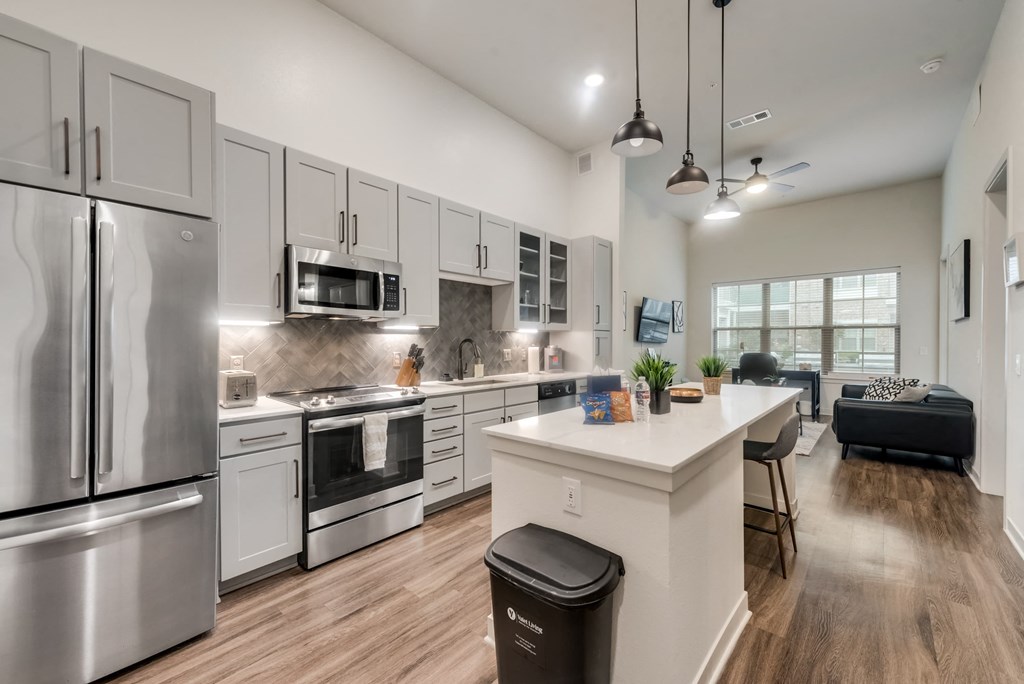 an open kitchen and living room with stainless steel appliances and white cabinets