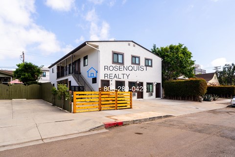 the exterior of rosemount realty with a yellow fence and a white building