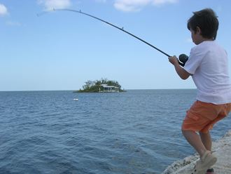 a little boy fishing in the ocean with a fishing rod