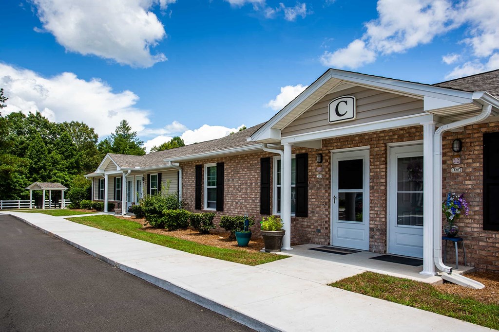 the front of a brick building with a porch and a sidewalk