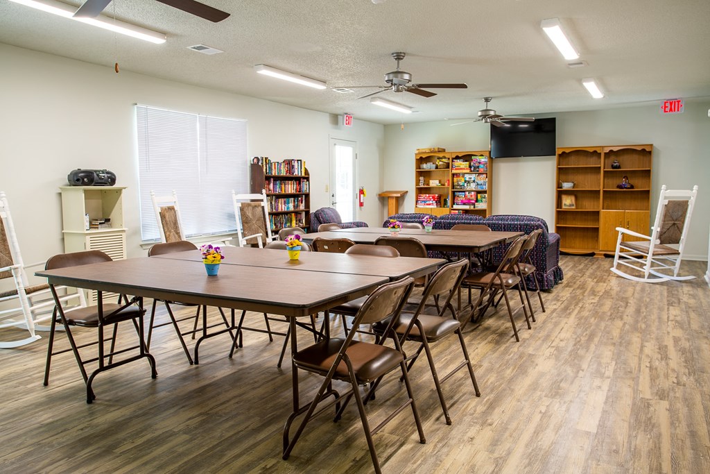 a community room with tables and chairs and a tv