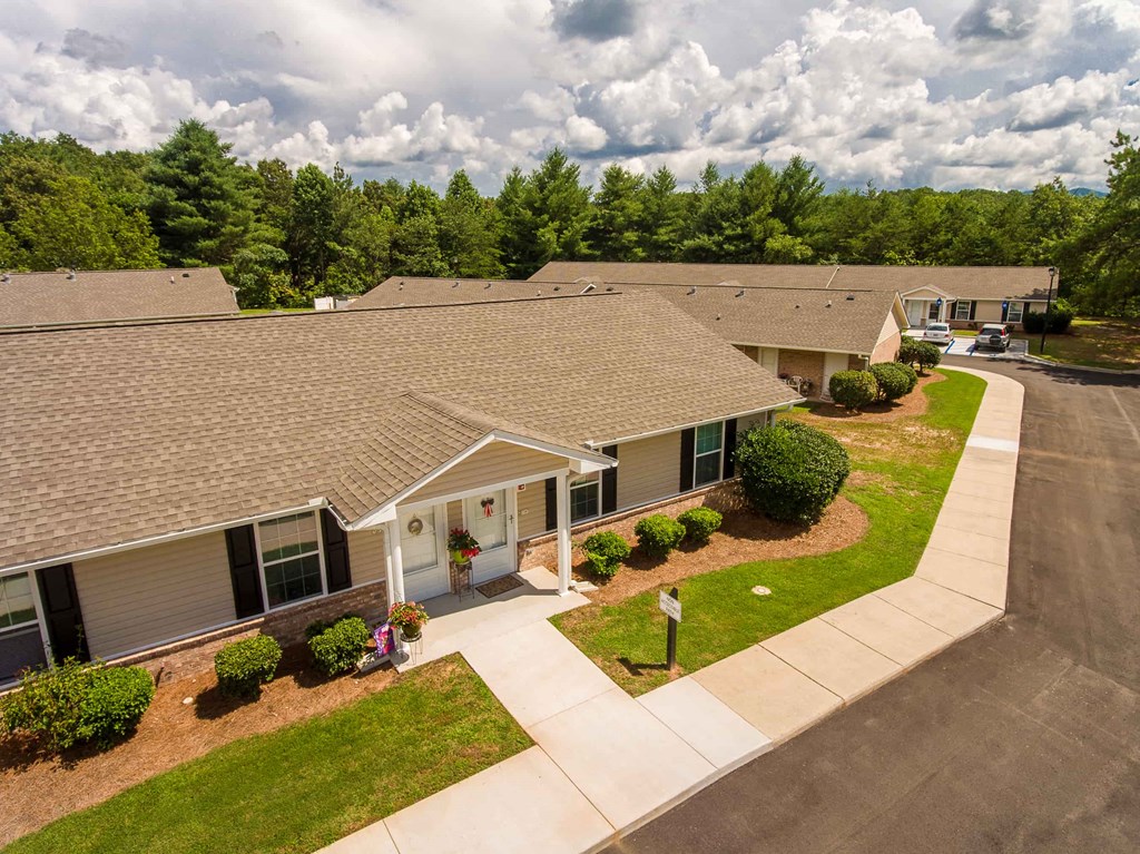an aerial view of a building with a parking lot and grass