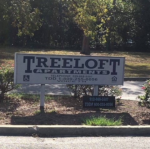 a sign that reads treeoot apartments in front of a park