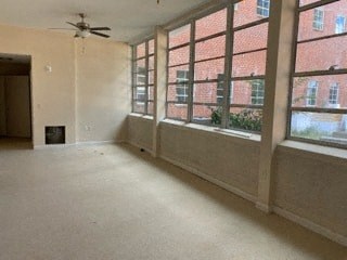an empty living room with large windows and a ceiling fan
