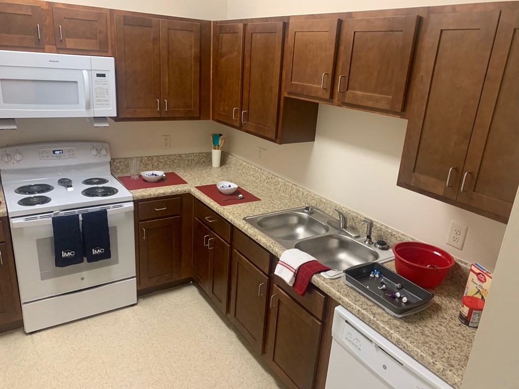 a kitchen with white appliances and wooden cabinets and granite counter tops