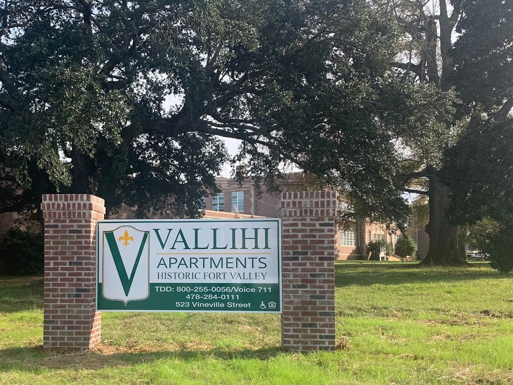 a sign for valley apartments in front of a tree