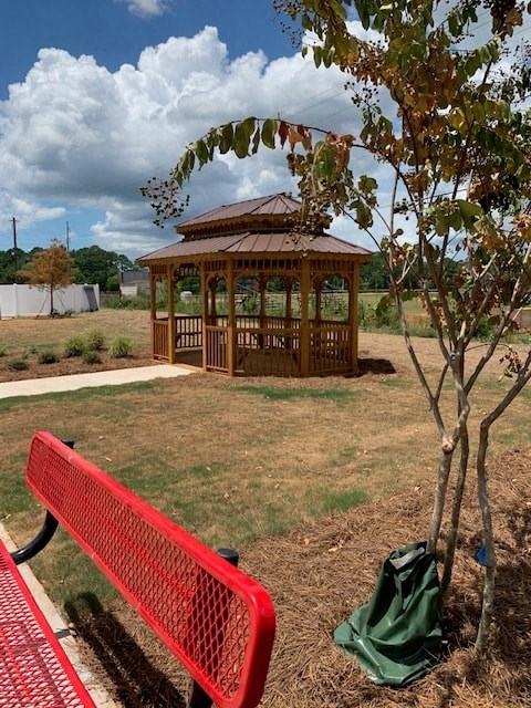 a gazebo in a park with a red bench