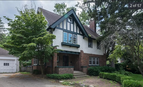 the front of a house with a driveway and trees