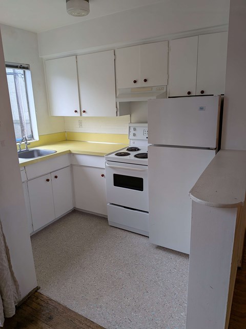 A white kitchen with a sink, stove, and refrigerator.