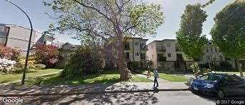 A street view of a residential area with a blue car parked on the side of the road.