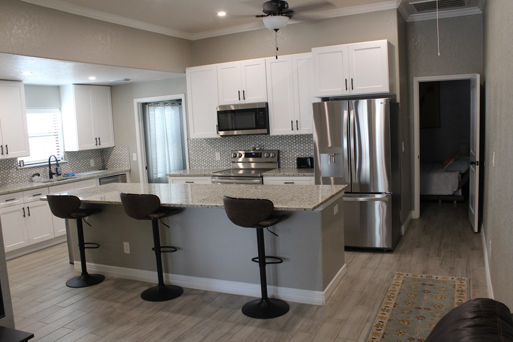 a kitchen with white cabinets and a island with bar stools