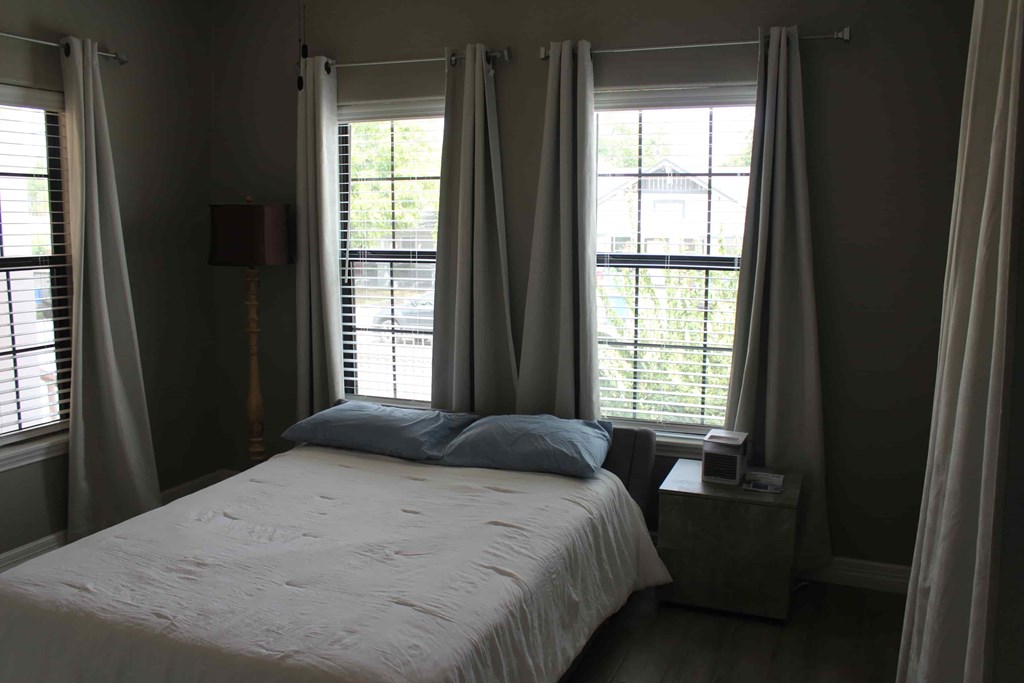 a bedroom with a bed and two windows