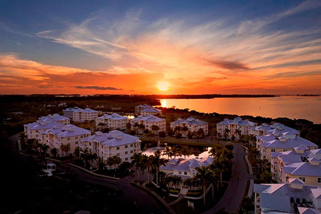 an aerial view of the resort with the sun setting over the water